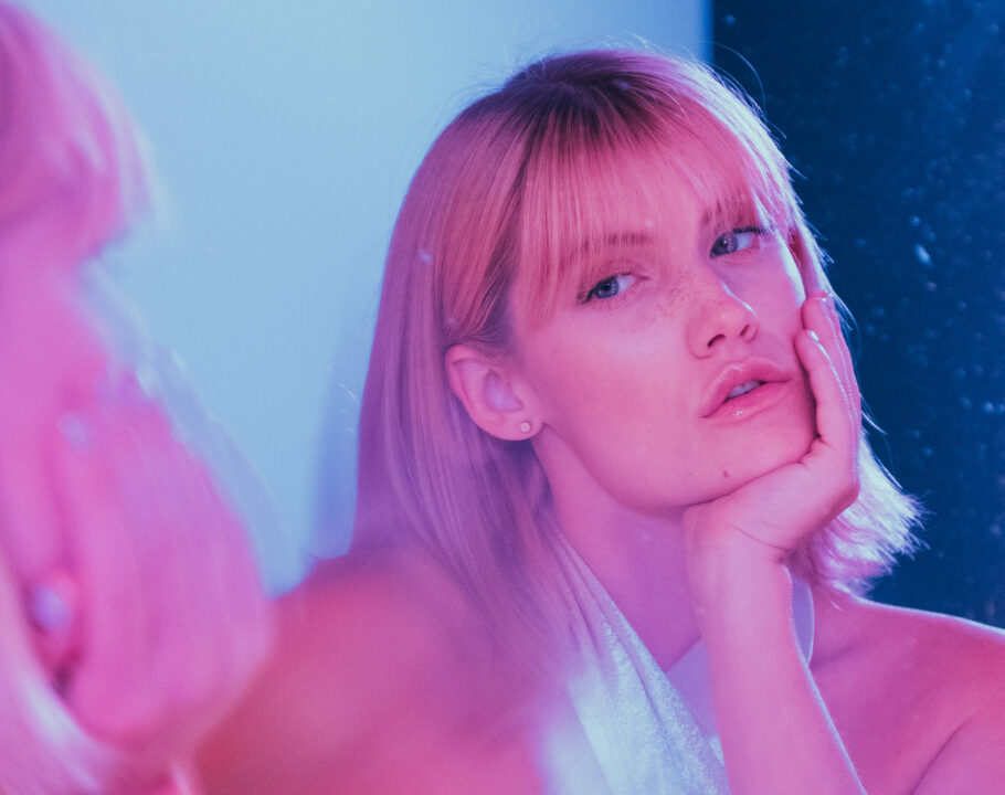 blonde model looking into mirror in pink and blue tinted image