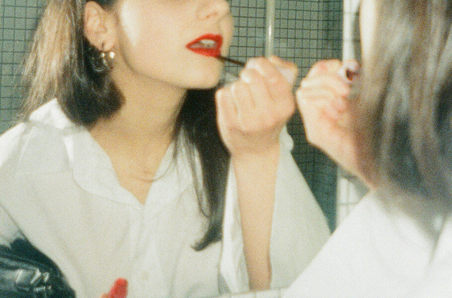 mirror shot of woman putting on red lipstick