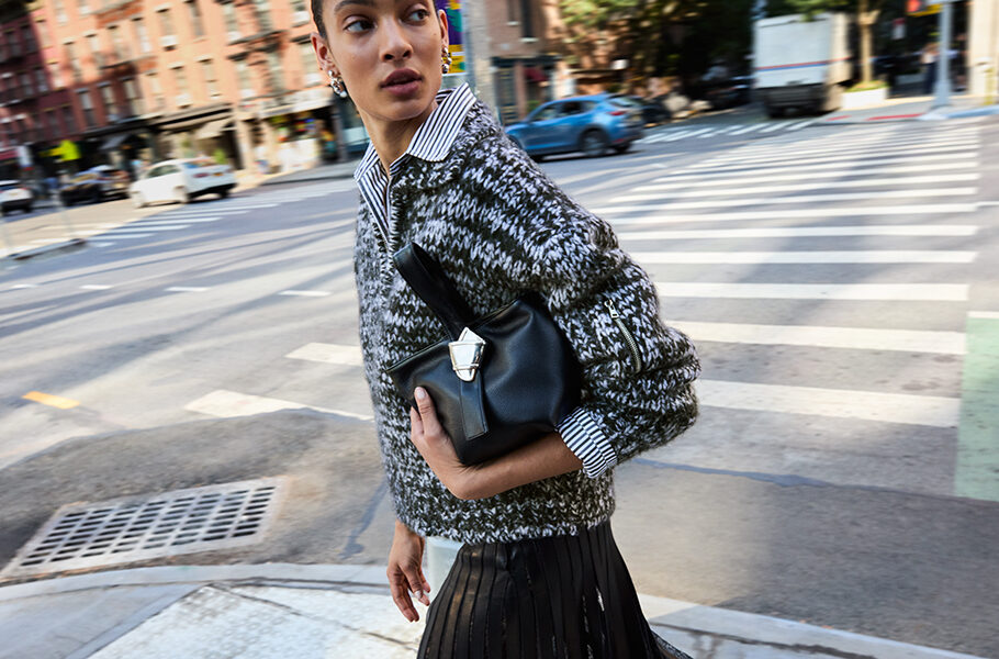 woman walking on city street with merit beauty and brandon maxwell bag