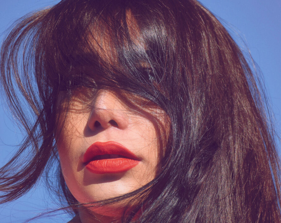 woman outdoors with bangs and hair in face wearing red lipstick