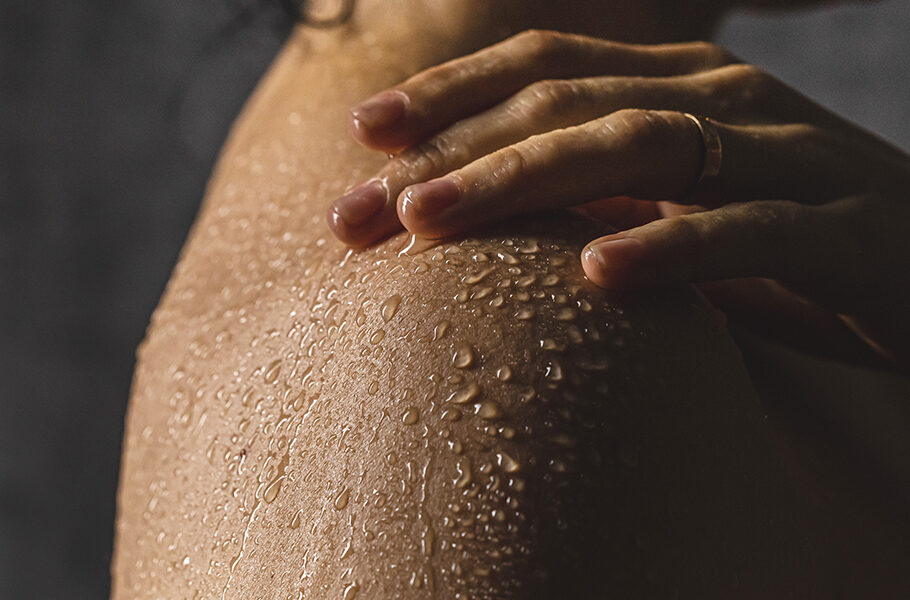 Detail of woman's shoulder with hand while taking a shower.